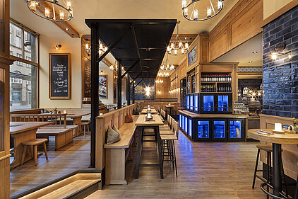 Langer Restaurantbereich mit Holztischen im Maximilians Berlin
